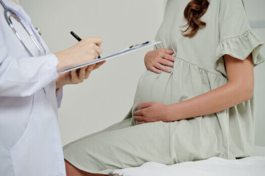 Gynecologist filling medical card of pregnant woman